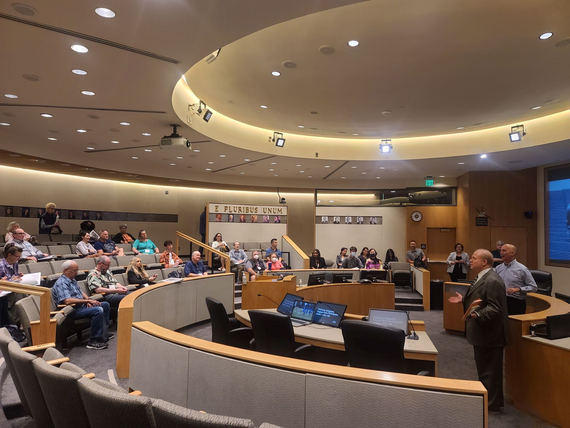 Presentation taking place in council chambers with man speaking to audience